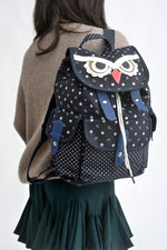 All Above Boutique navy canvas backpack with white polka dots and a playful owl face design. Features adjustable straps and multiple pockets.