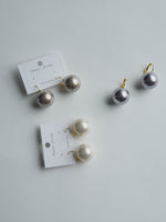 All Above Boutique pearl drop earrings in cream and grey, made with stainless steel and synthetic pearls. Classic design.