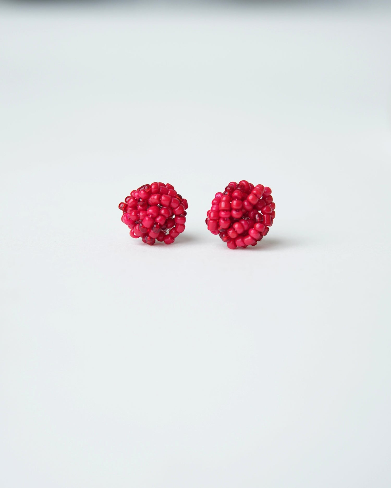 All Above Boutique small red beaded knot stud earrings.