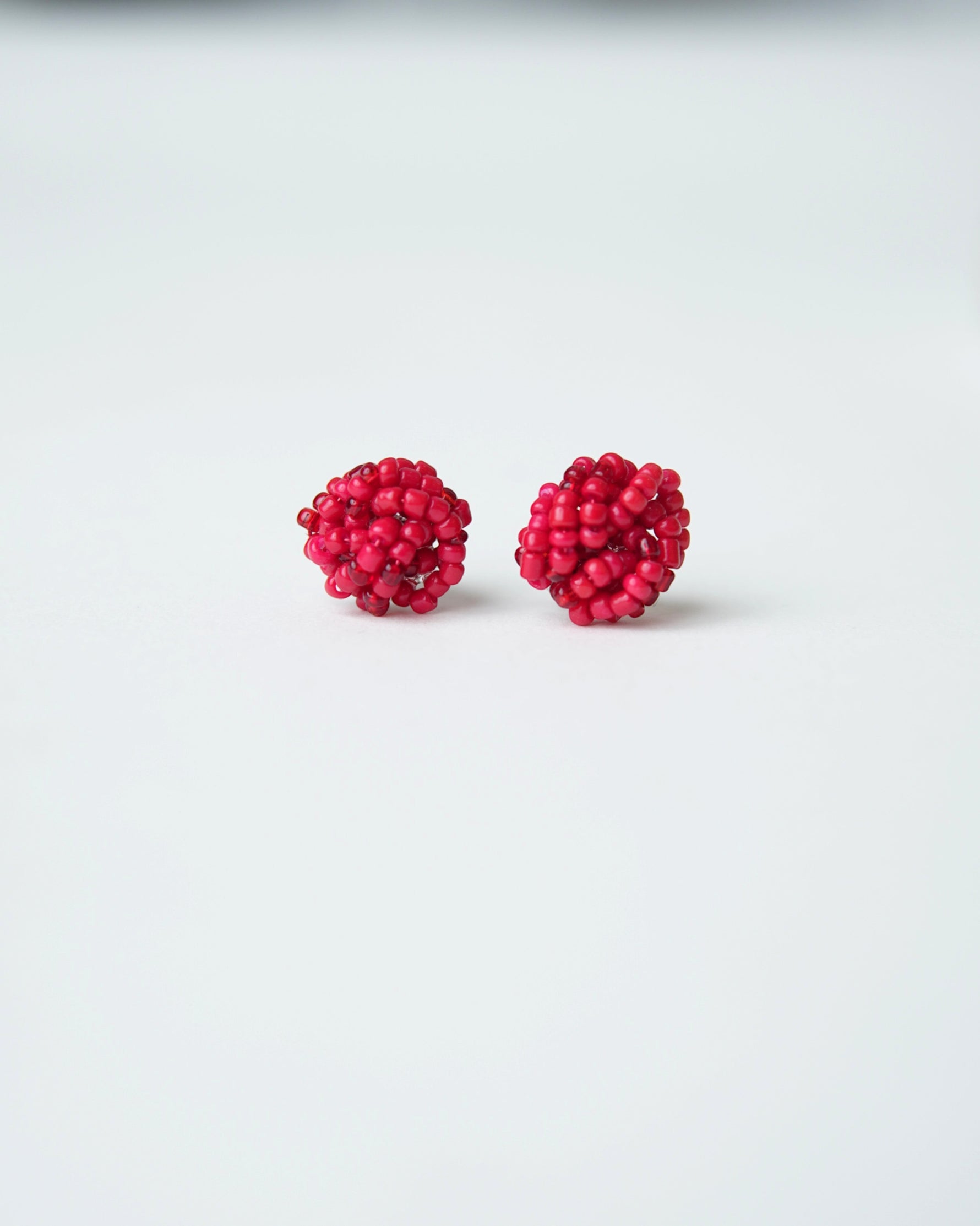 All Above Boutique small red beaded knot stud earrings.