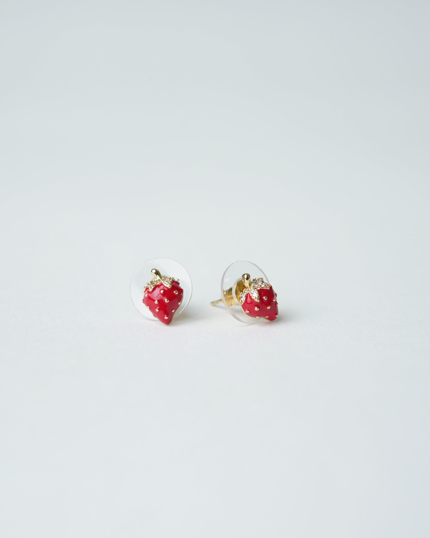 All Above Boutique small red strawberry stud earrings with gold accents and clear backing.