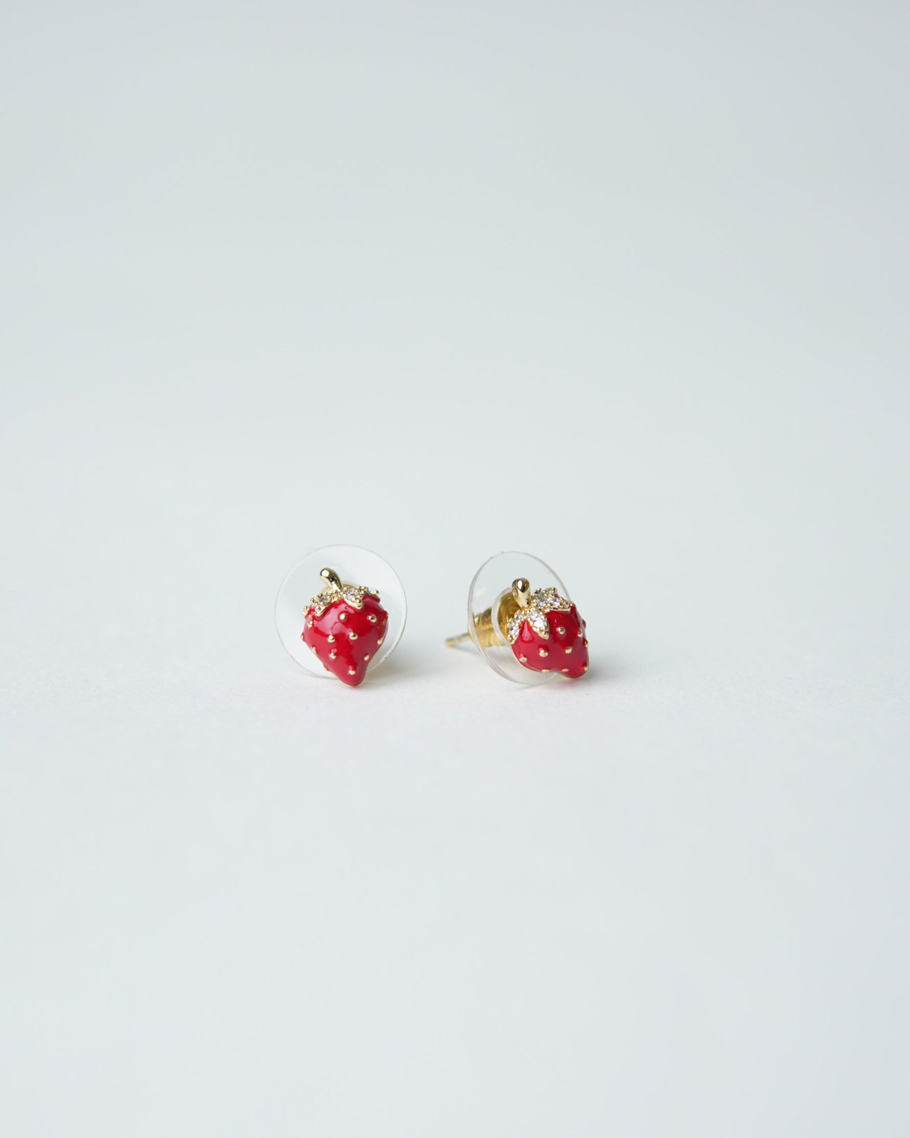 All Above Boutique small red strawberry stud earrings with gold accents and clear backing.