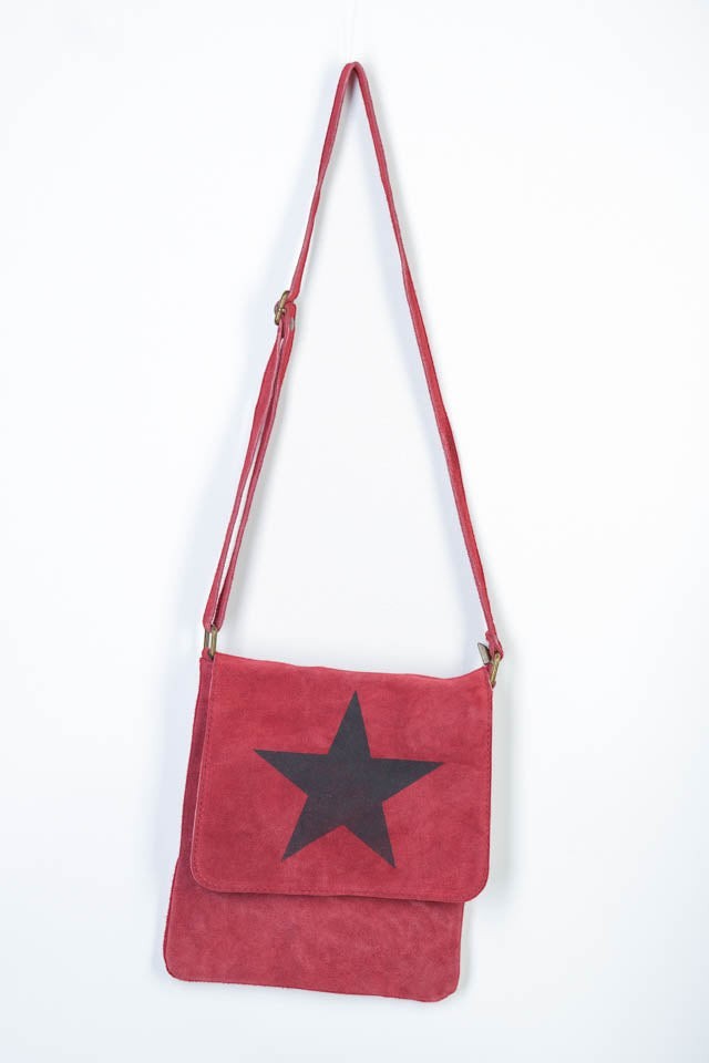 All Above Boutique red suede crossbody bag with black star detail and adjustable strap.