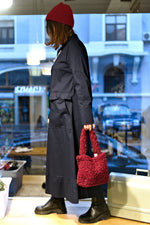 All Above Boutique red teddy fabric tote bag with double handles and magnetic snap closure, worn by a model in a dark coat and red beanie.