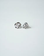 All Above Boutique silver-tone knot stud earrings with a polished finish and floral-inspired design.