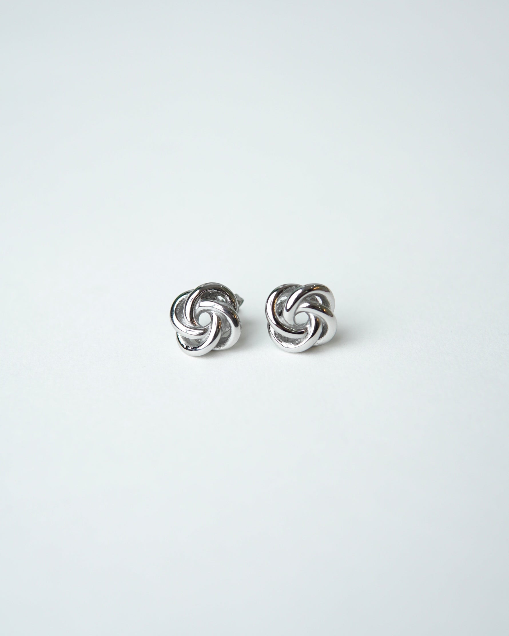 All Above Boutique silver knot stud earrings with a polished metallic finish, featuring a floral-inspired design.