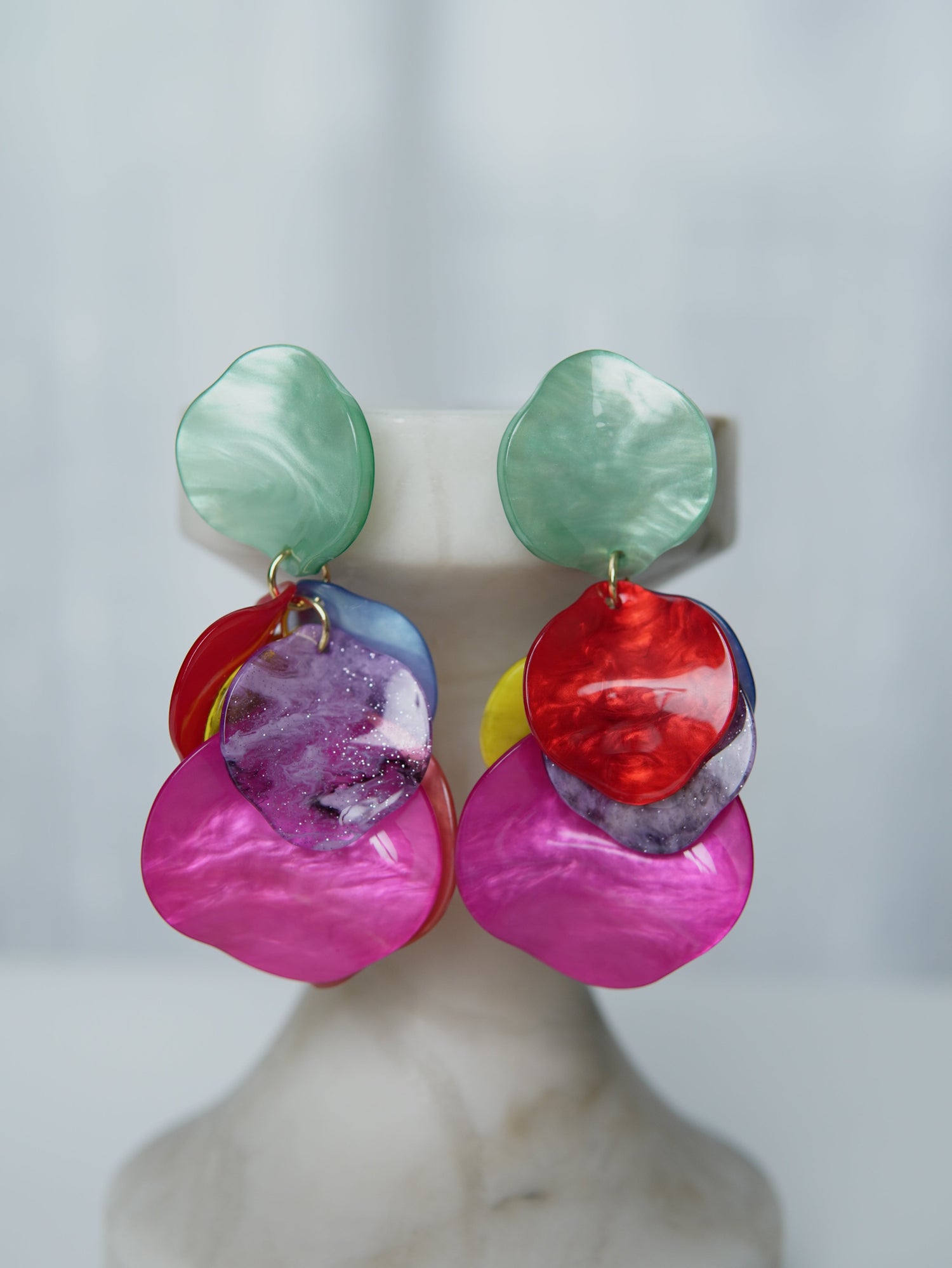 All Above Boutique statement earrings with layered, iridescent petals in pink, red, yellow, blue, and green.