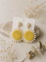 All Above Boutique daisy flower straw earrings with yellow centers and white petals, perfect for summer.