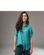 All Above Boutique teal rayon relaxed fit short sleeve button-up shirt with asymmetric hem and rolled cuffs.
