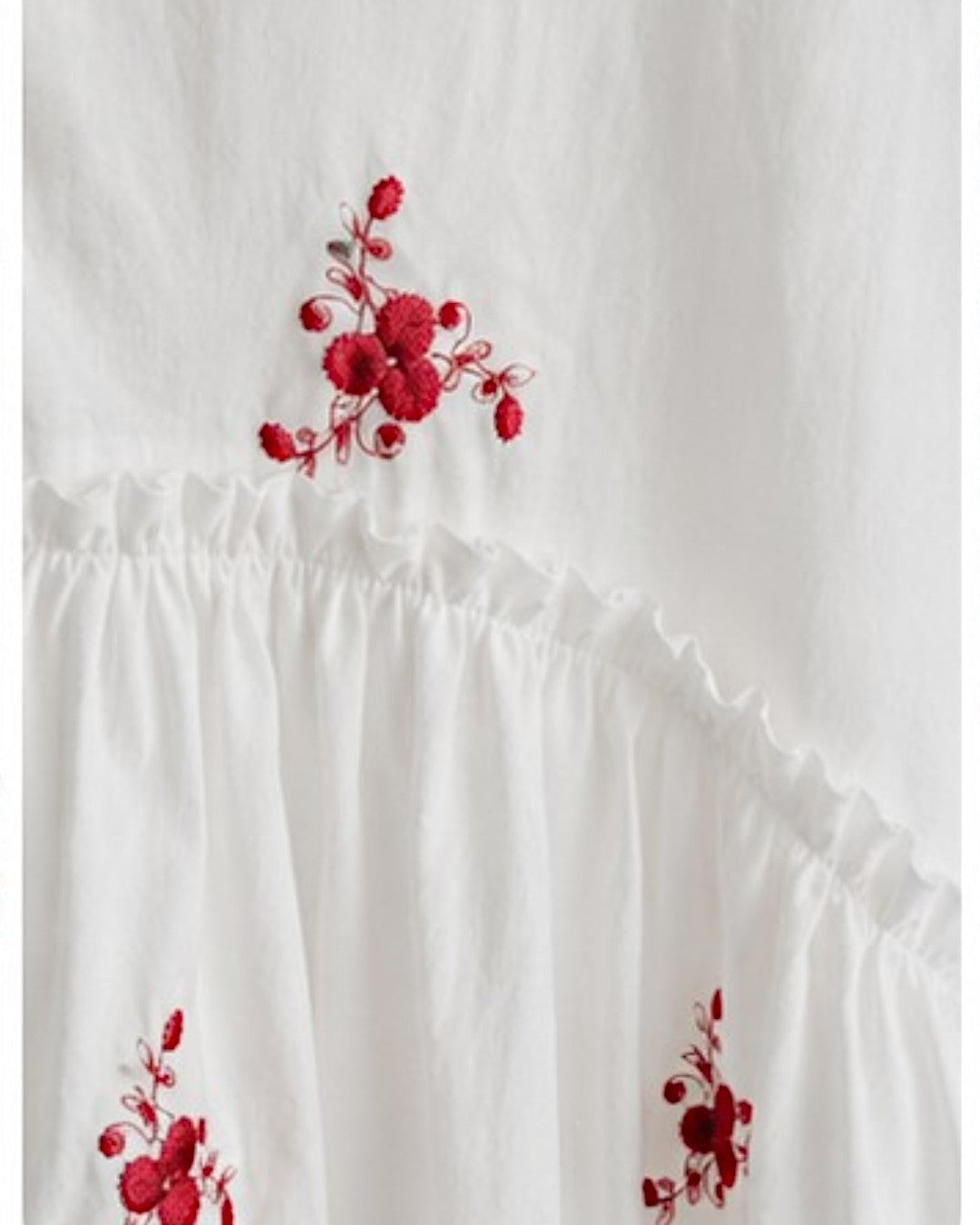 All Above Boutique white cotton blend oversized shirt with red floral embroidery and ruffled details.