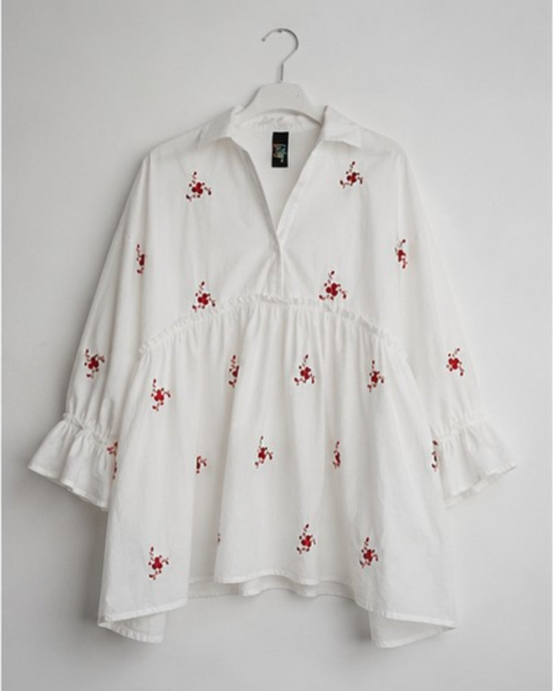 All Above Boutique white cotton blend oversized shirt with red floral embroidery and 3/4 ruffled sleeves.