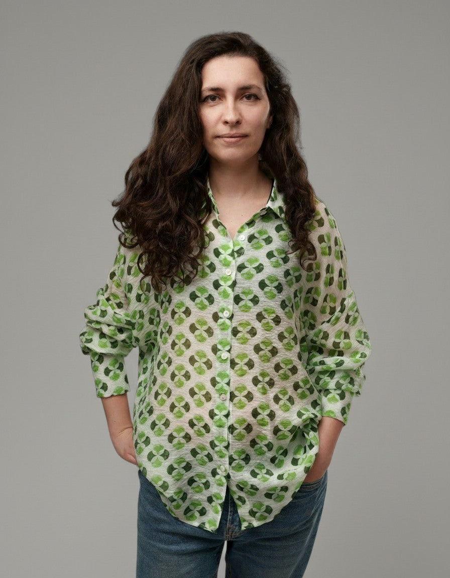All Above Boutique white rayon shirt with green clover print, classic collar, long sleeves, and asymmetric hem.