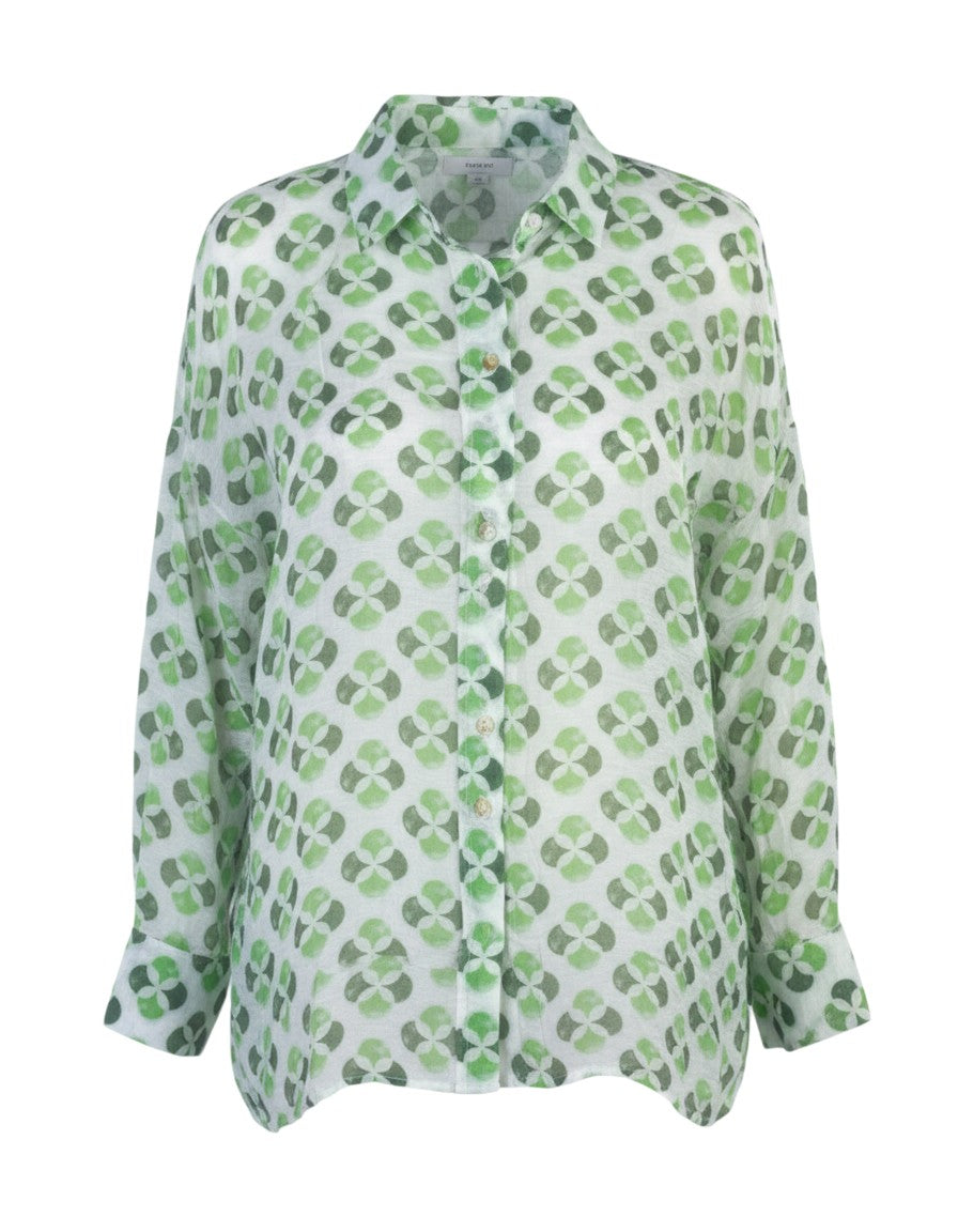 All Above Boutique white rayon shirt with green clover print, classic collar, long sleeves, and asymmetric hem.