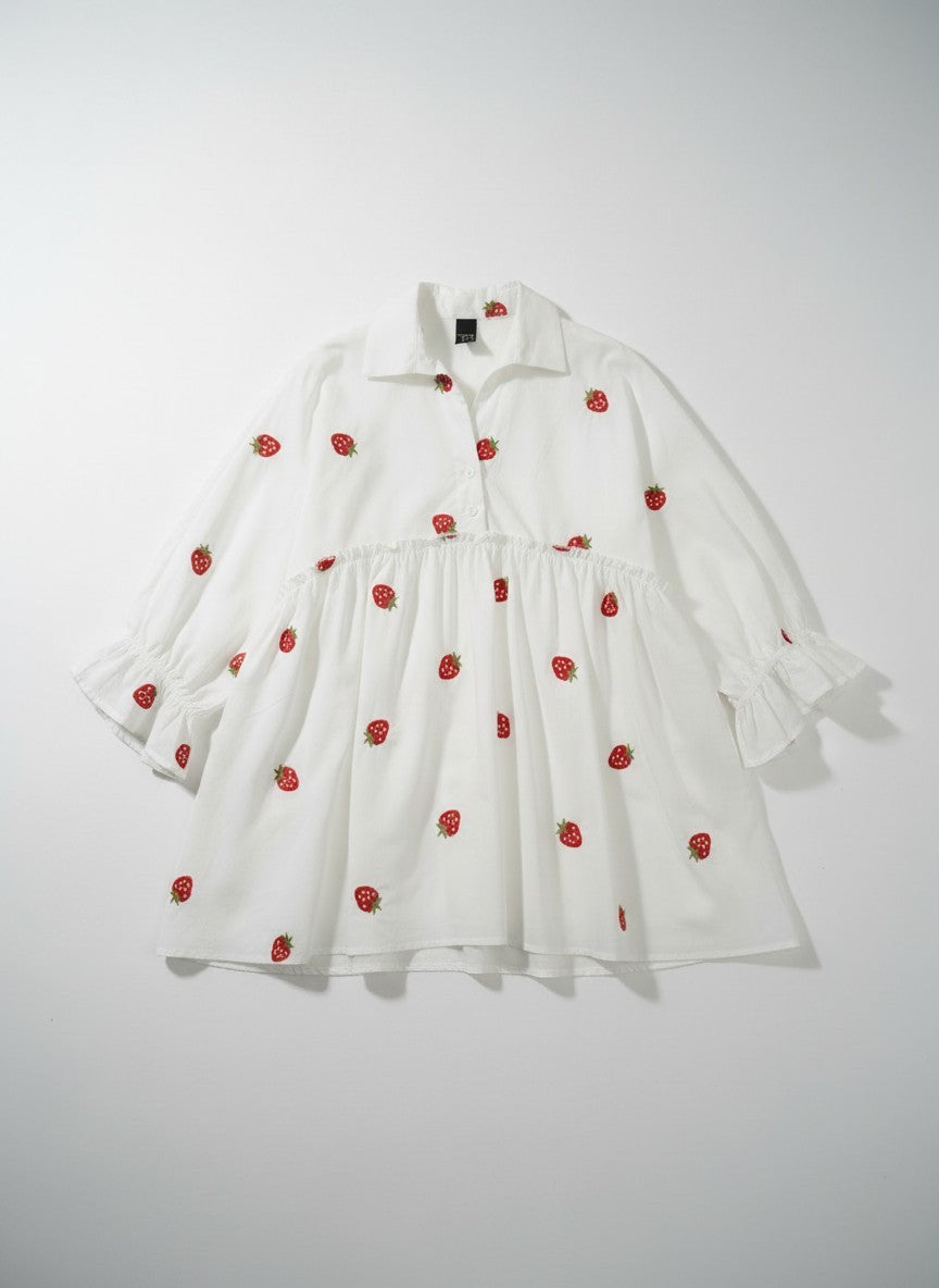 All Above Boutique white oversized shirt with 3/4 sleeves and a playful strawberry print. Features a ruffled hem and collar.