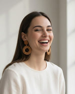 All Above Boutique boho style round woven wood statement earrings on a smiling woman.