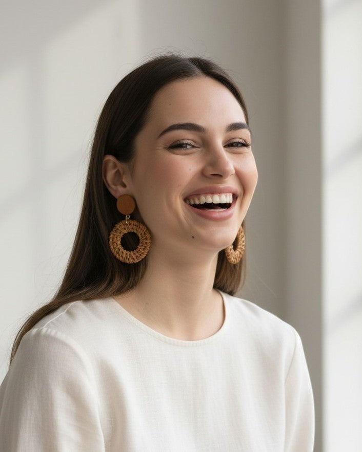 All Above Boutique boho style round woven wood statement earrings on a smiling woman.