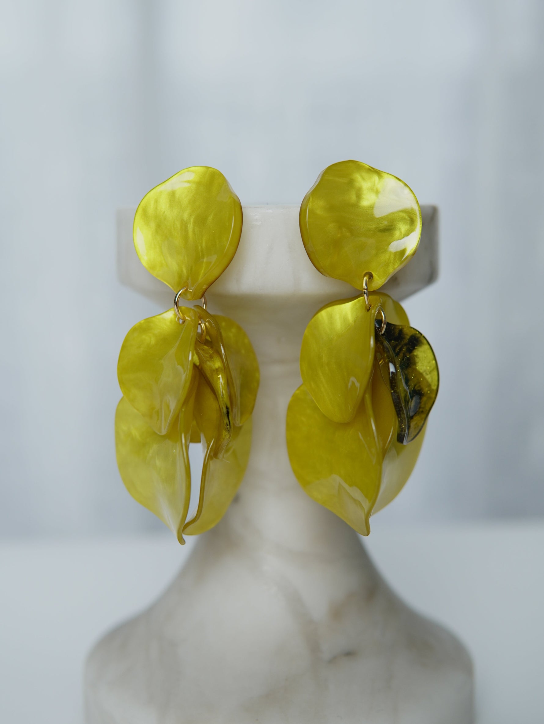 All Above Boutique yellow statement earrings with layered petal design and iridescent finish.