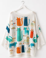 Bluză albă oversize din tricot cu imprimeu colorat cu pisici, fotografiată pe umeraș alb. All Above Boutique.