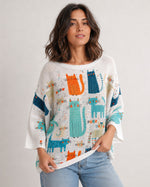 Bluză albă oversize cu imprimeu pisici colorate, purtată de model din unghi trei sferturi. All Above Boutique.