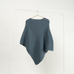 Capă tricotată cu 30% lână, de culoare bleu, cu croială asimetrică.