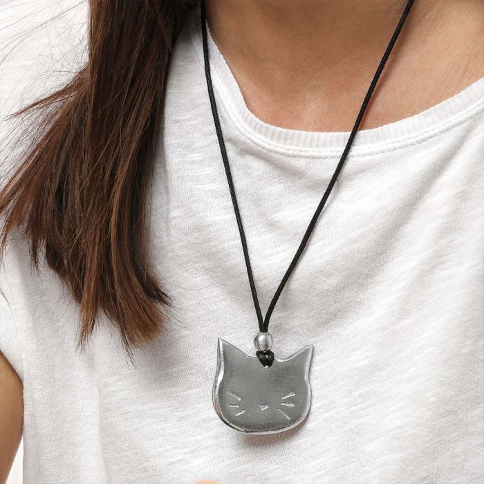 Colier handmade din aluminiu reciclat purtat de o femeie, cu pandantiv argintiu în formă de pisică și șnur textil negru – design jucăuș și modern.