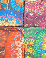 Detaliu al patru eșarfe viu colorate, cu imprimeuri florale vibrante.