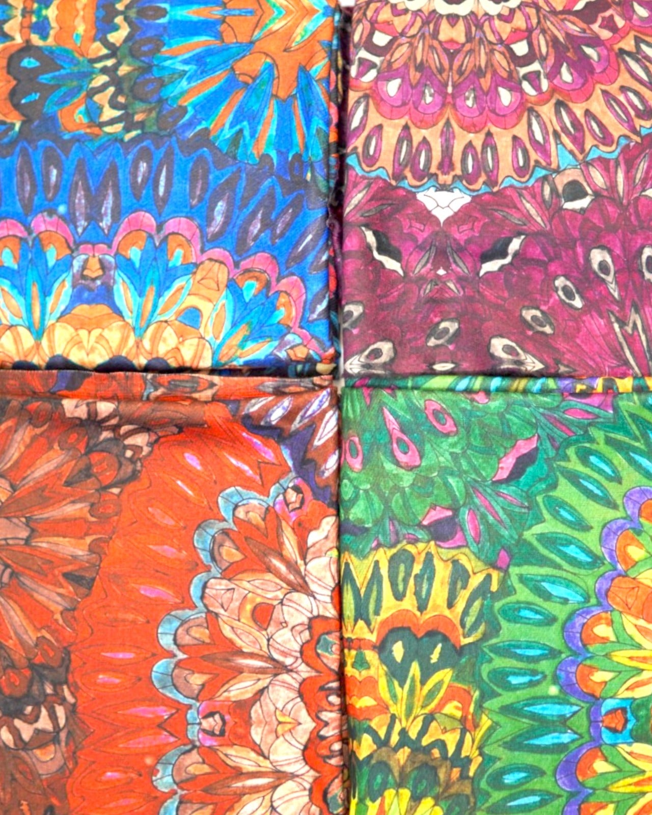 Detaliu al patru eșarfe viu colorate, cu imprimeuri florale vibrante.