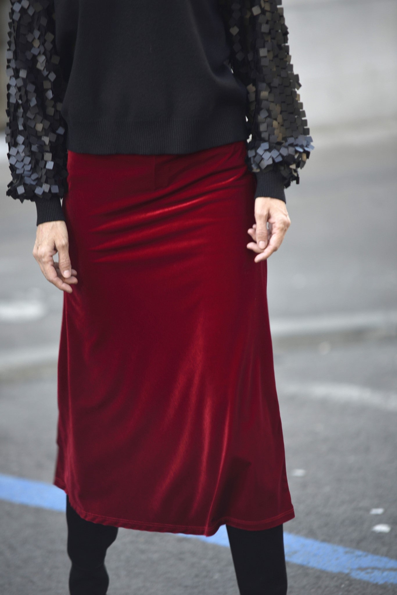 Fustă midi din catifea roșu închis, cu talie elastică, purtată cu un pulover cu mâneci accesorizate, ideală pentru un look elegant și sofisticat.