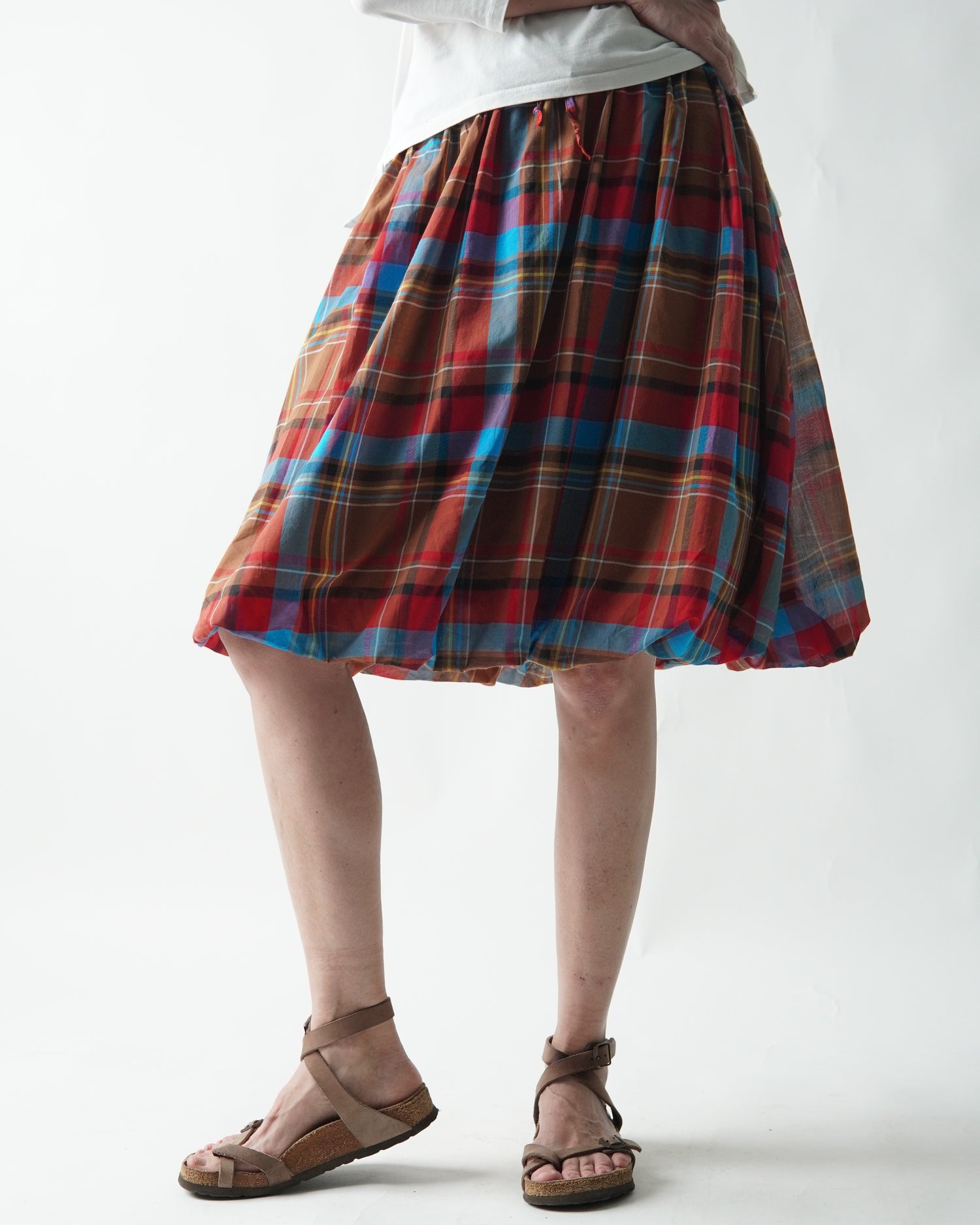 Fustă scurtă gogoșar în carouri, purtată din profil, cu aspect lejer