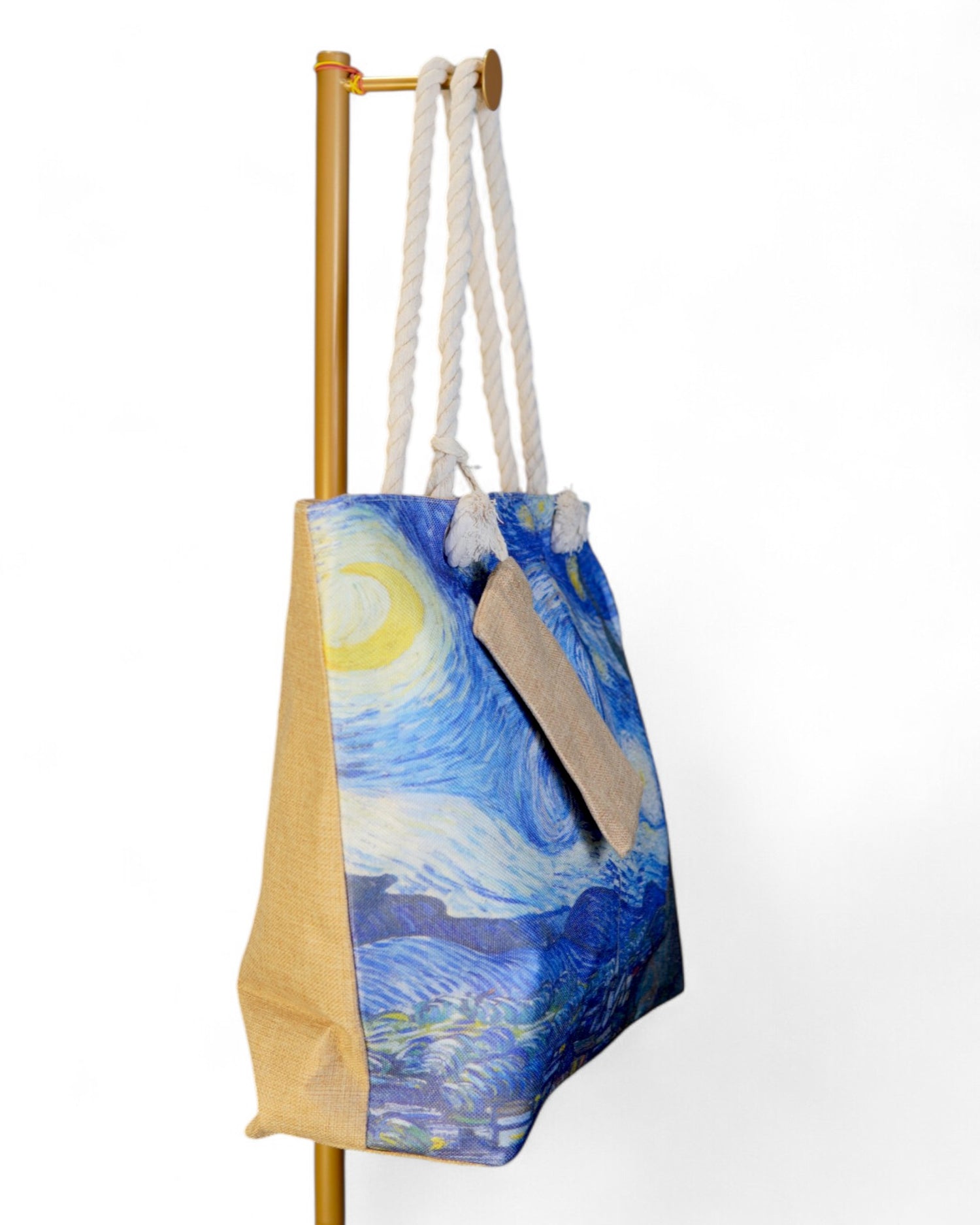 Geantă mare de plajă cu imprimeu inspirat de „Noaptea înstelată” de Van Gogh, vizualizată din lateral, cu detalii ale mânerelor din sfoară și material din pânză texturată.
