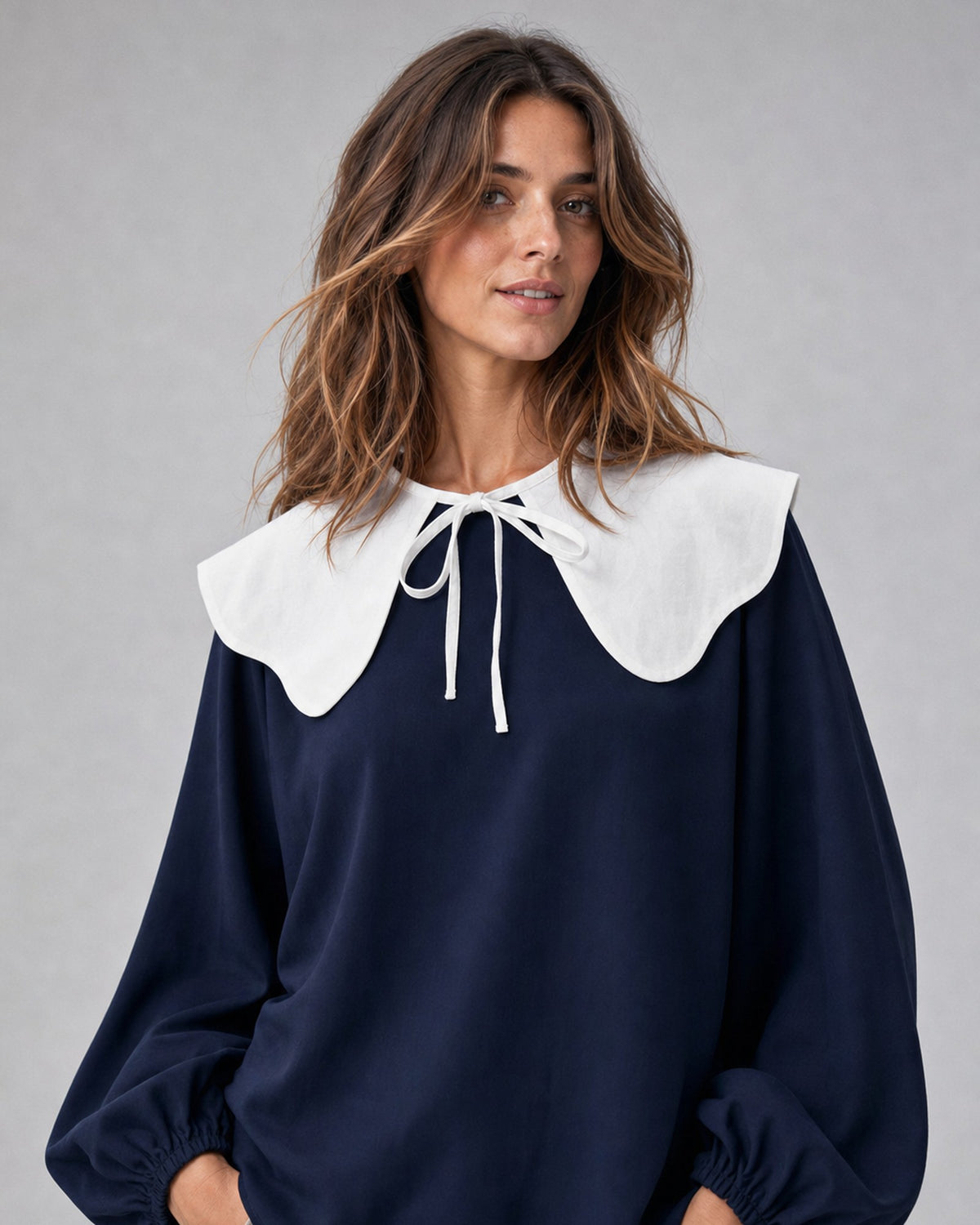 Accesoriu guler ondulat alb cu fundă, purtat peste o bluză bleumarin, All Above Boutique