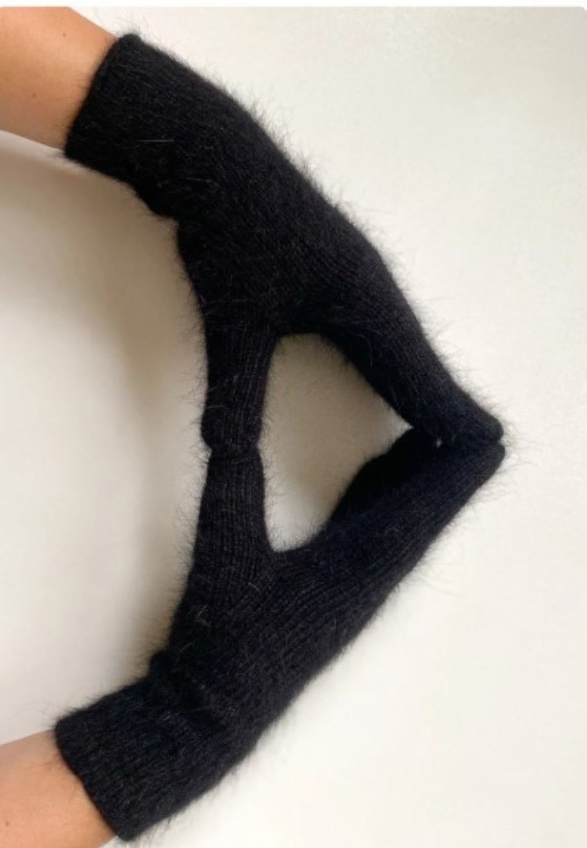 Mănuși pufoase negre din mohair purtate pe mâini, formând un triunghi cu degetele unite.
