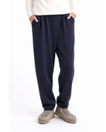 Pantaloni conici bleumarin cu pliuri pareo și talie elastică, purtați cu mâinile în buzunare - All Above Boutique