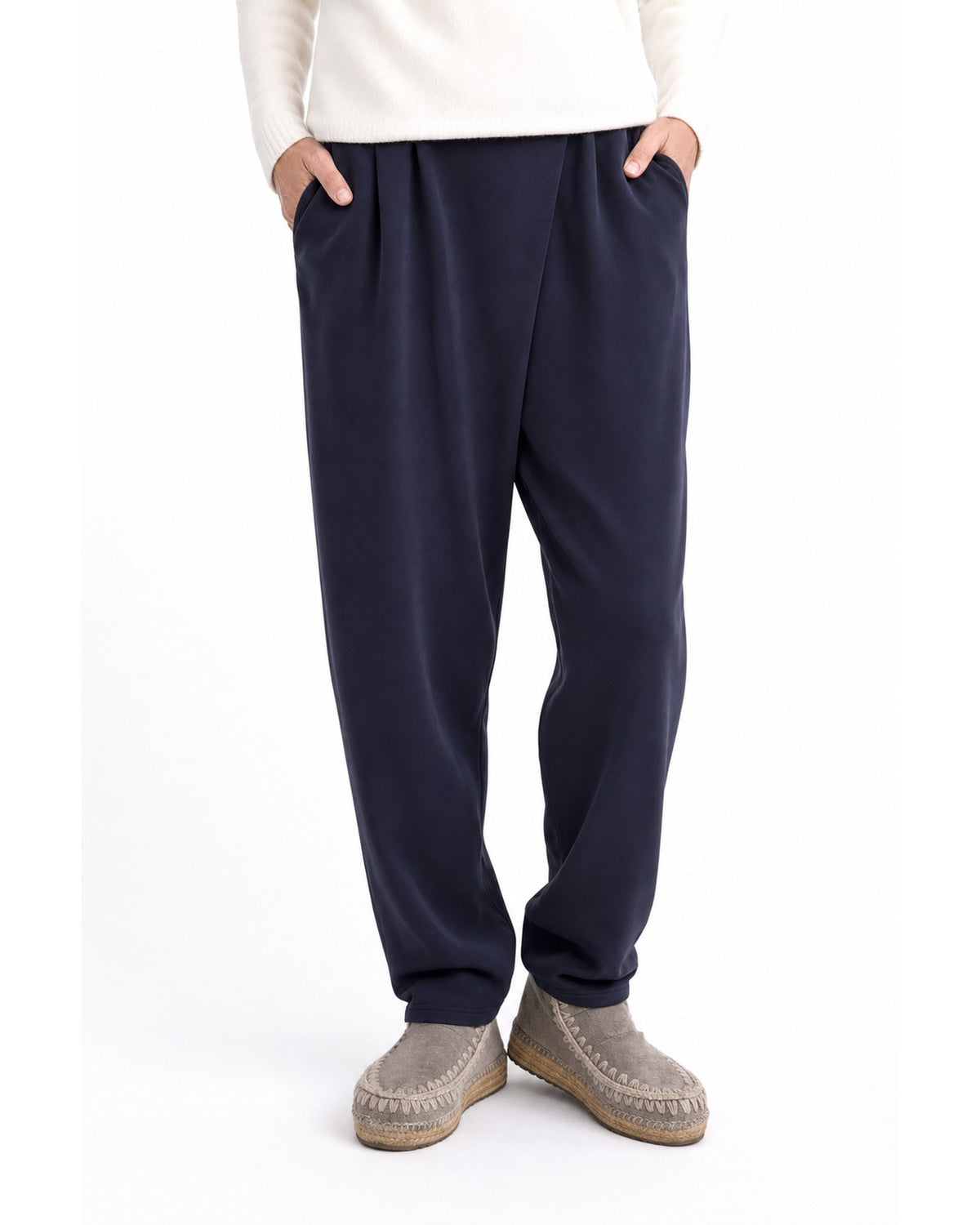 Pantaloni conici bleumarin cu pliuri pareo și talie elastică, purtați cu mâinile în buzunare - All Above Boutique