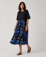 Rochie midi cu print abstract albastru și negru, prezentată pe model în mișcare în studio