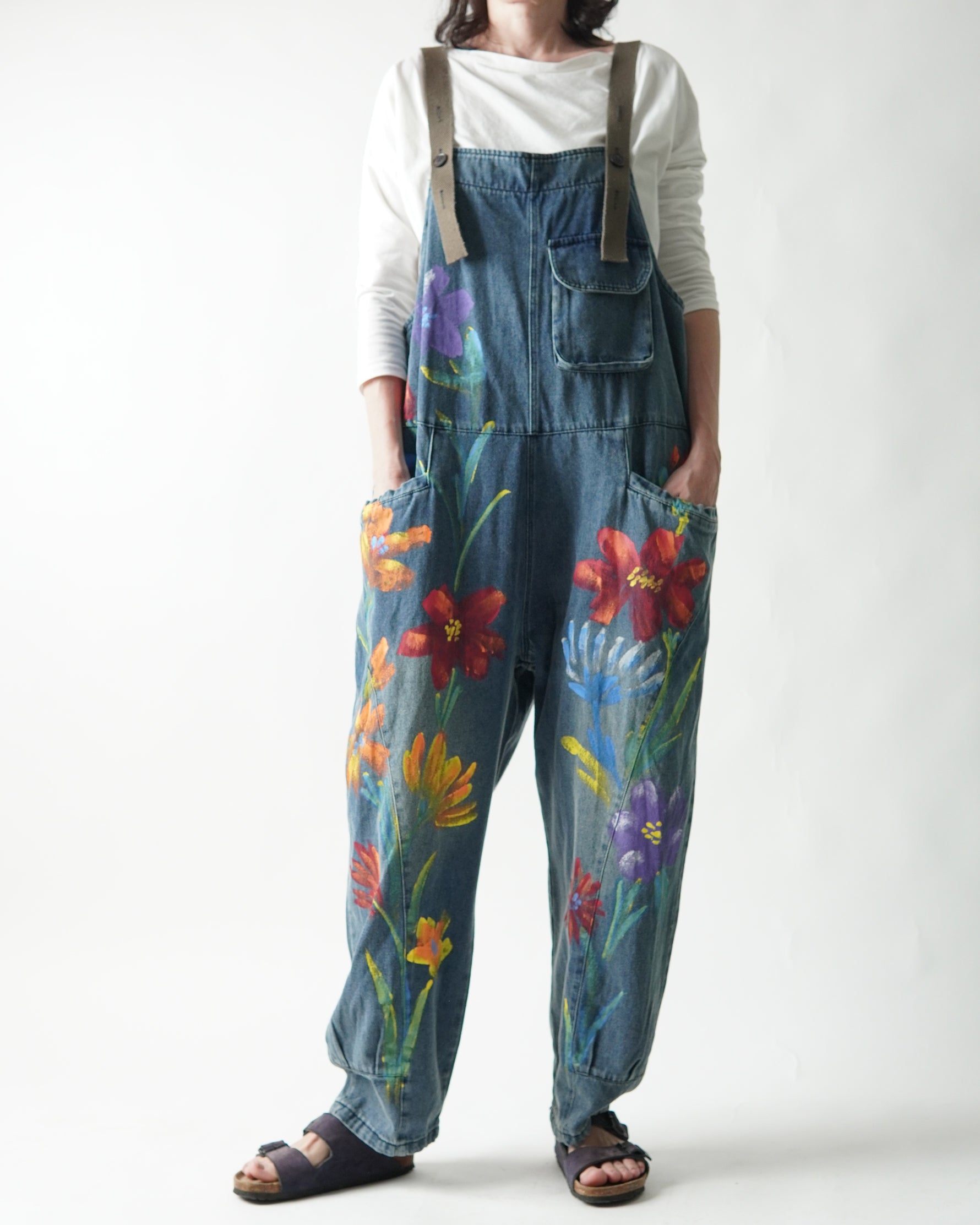 Salopetă din jeans pictată manual cu motive florale purtată pe model
