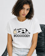 Femeie purtând tricou alb cu imprimeu văcuță și mesaj Moooody