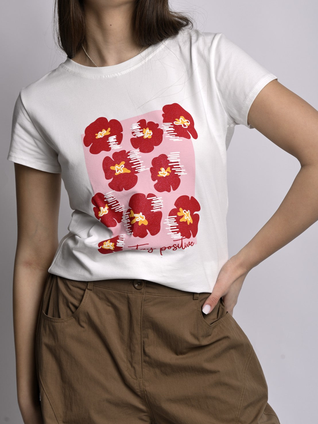 Tricou alb cu imprimeu floral roșu purtat de model, stil casual